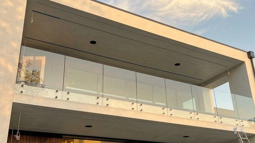 Balcony glass railing on matte black standoffs across the back of a Clyde Hill, WA home, installed by IGo Green Enterprises