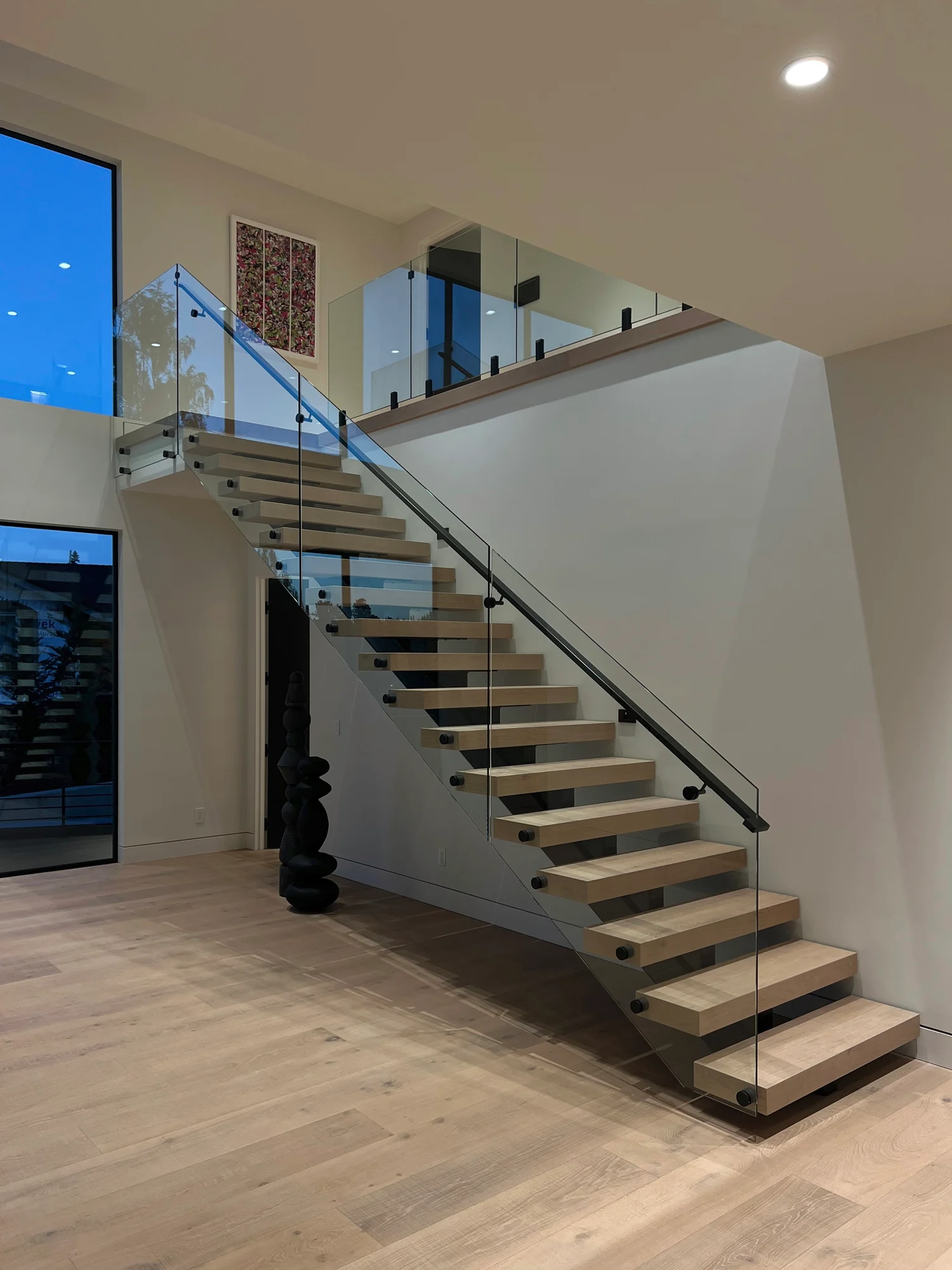 Floating staircase with a frameless glass railing on black standoffs, by IGo Green Enterprises in Clyde Hill, WA