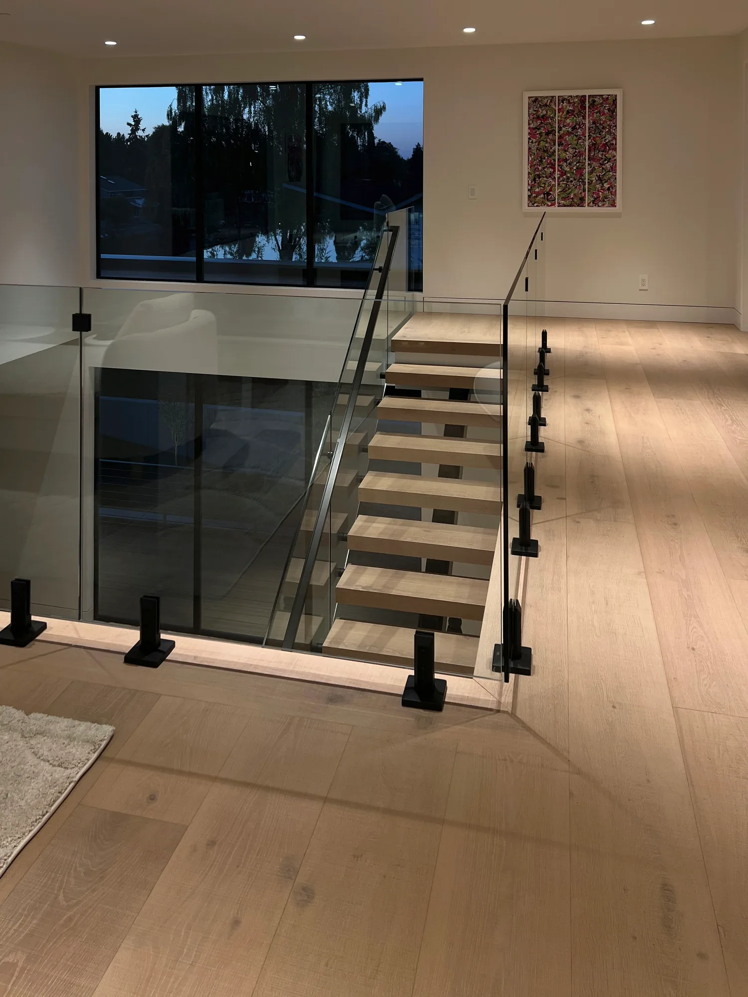 Glass railings framing the top of a floating staircase, installed by IGo Green Enterprises in Clyde Hill, WA