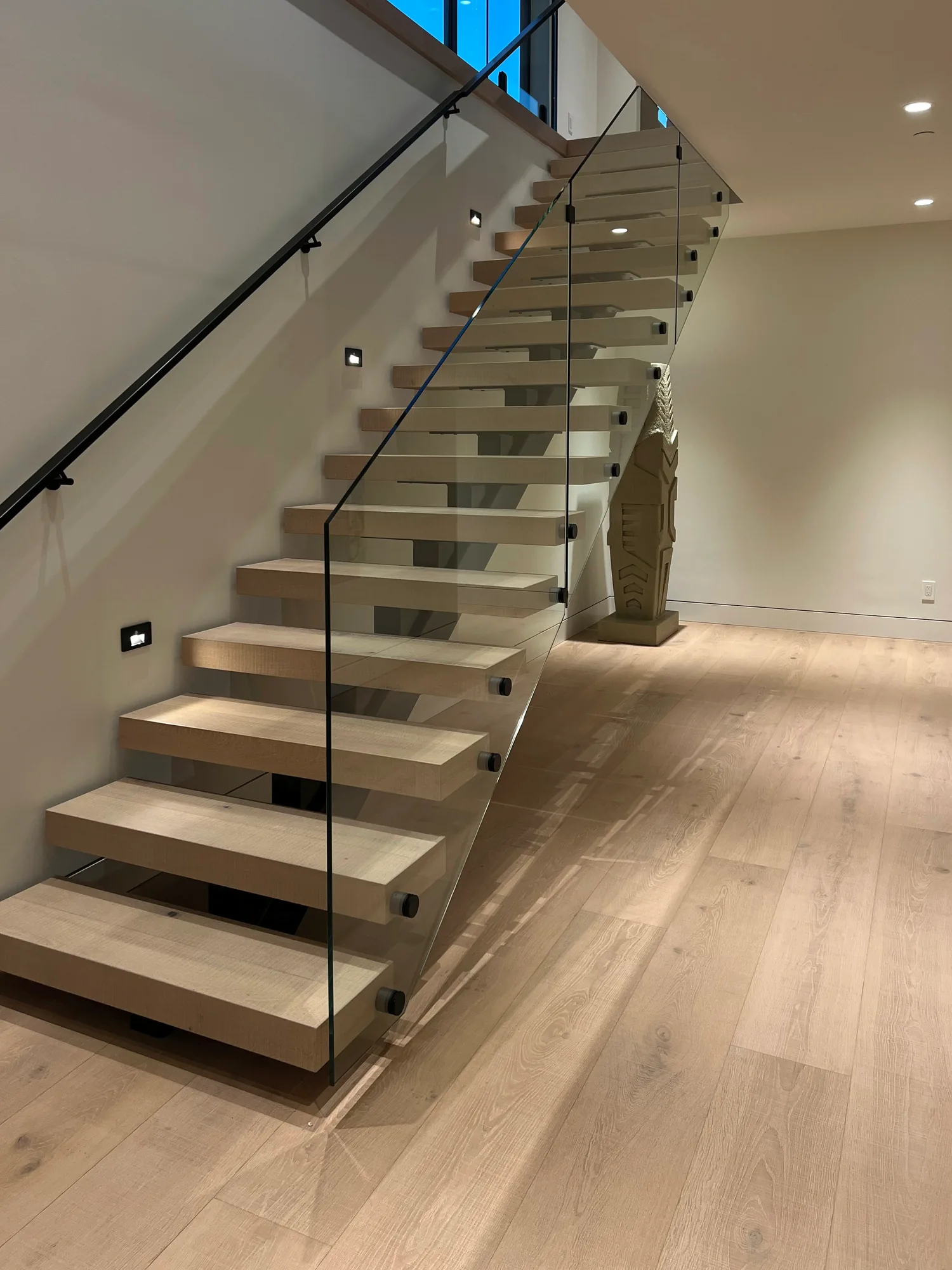Glass stair railing on black standoffs along floating oak treads, installed by IGo Green Enterprises in Clyde Hill, WA
